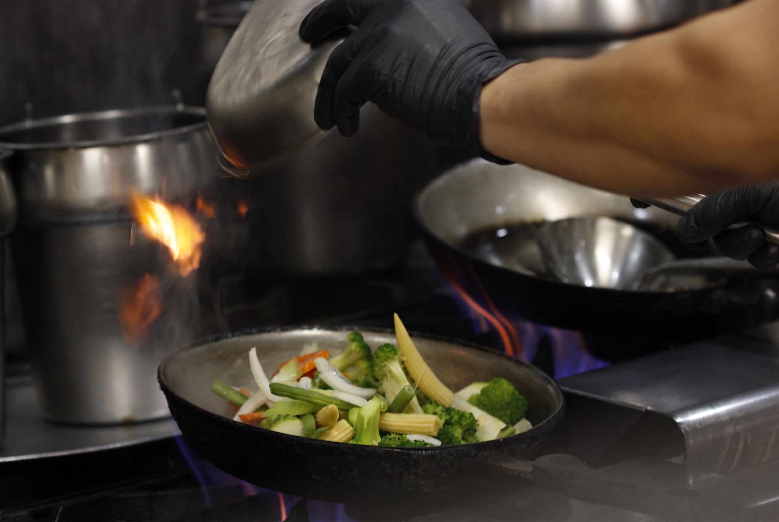 Fresh vegetables in a wok over open flame