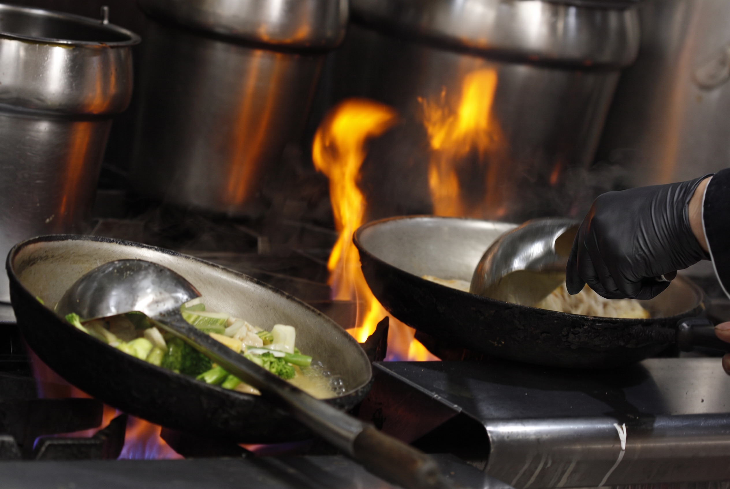 Two pans searing over a fiery burner